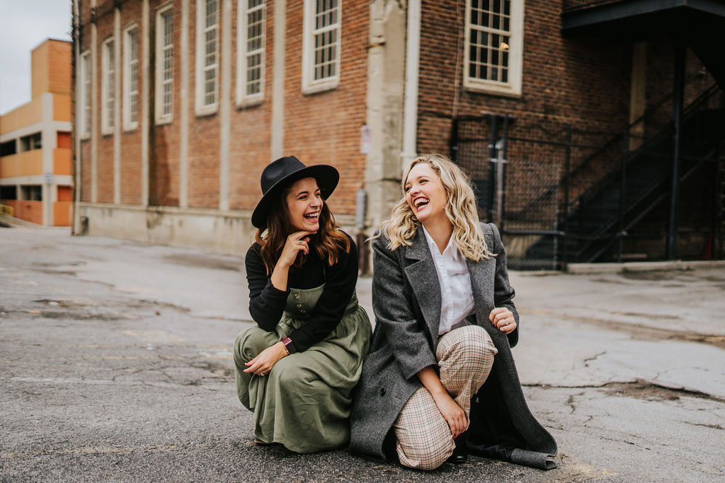 two woman sitting on street in Knoxville laughing during Novelbound podcast book shoot