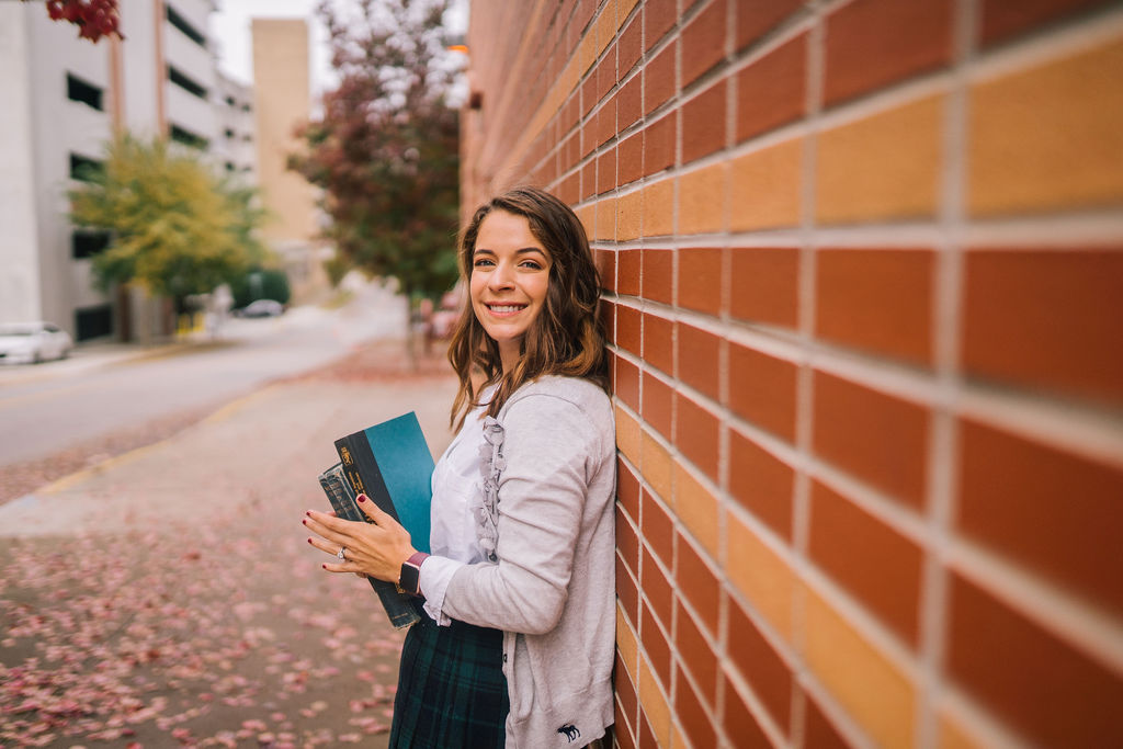 young women leaning against a brick wall holding favorite books