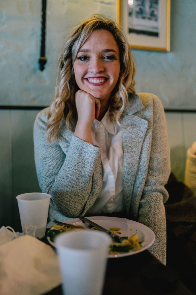 girl smiling at cafe restaurant table in front of plate and cup 